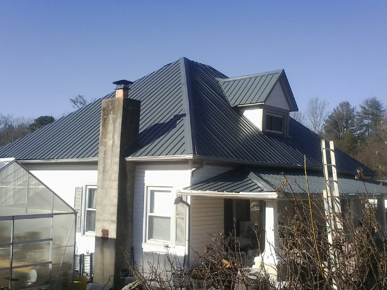 Dark blue standing seam metal roof on a white farmhouse with dormer — Slate & Tile Roof Repair by Roofing Brothers in Jersey