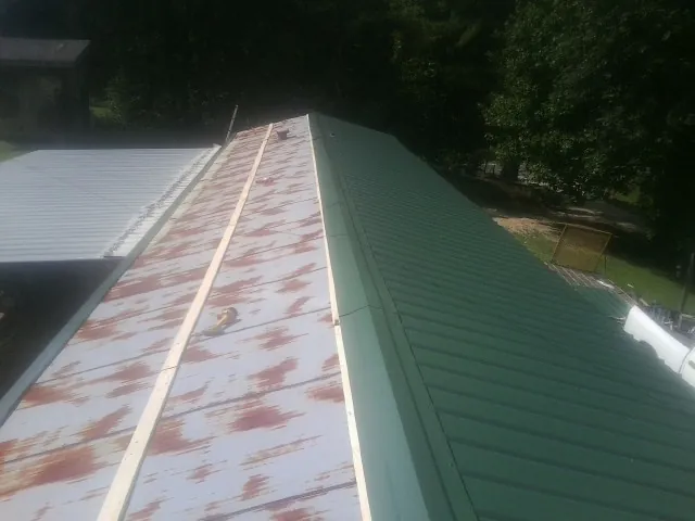 Old rusted panels beside newly installed green metal roofing — Wind Damage Roof Repair by Roofing Brothers in Jersey