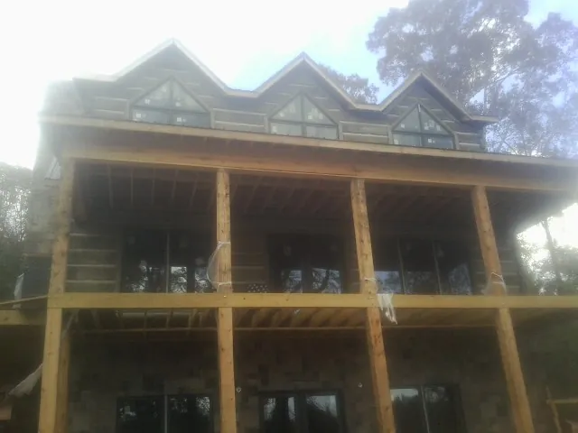 Dormers and porch framing on a large log home under construction — Roof Coating work by our crew in Jersey