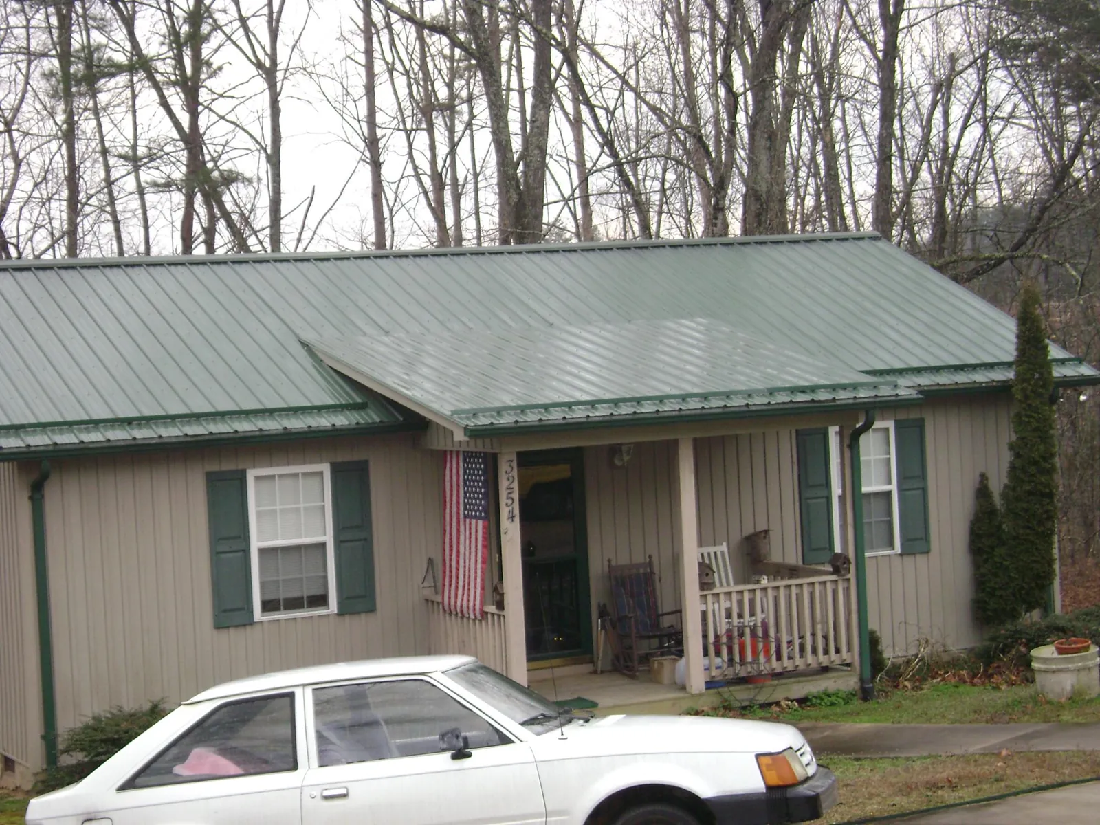 Green metal roof and front porch on a tan sided cottage in Jersey