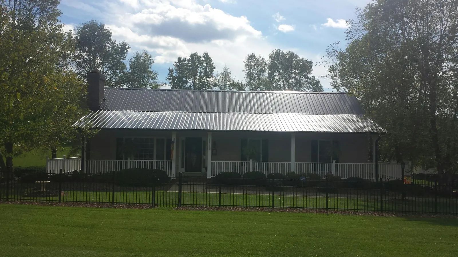 Gray metal roof on a brick ranch with a full width front porch — Gutter Guard Installation work by our crew in Jersey