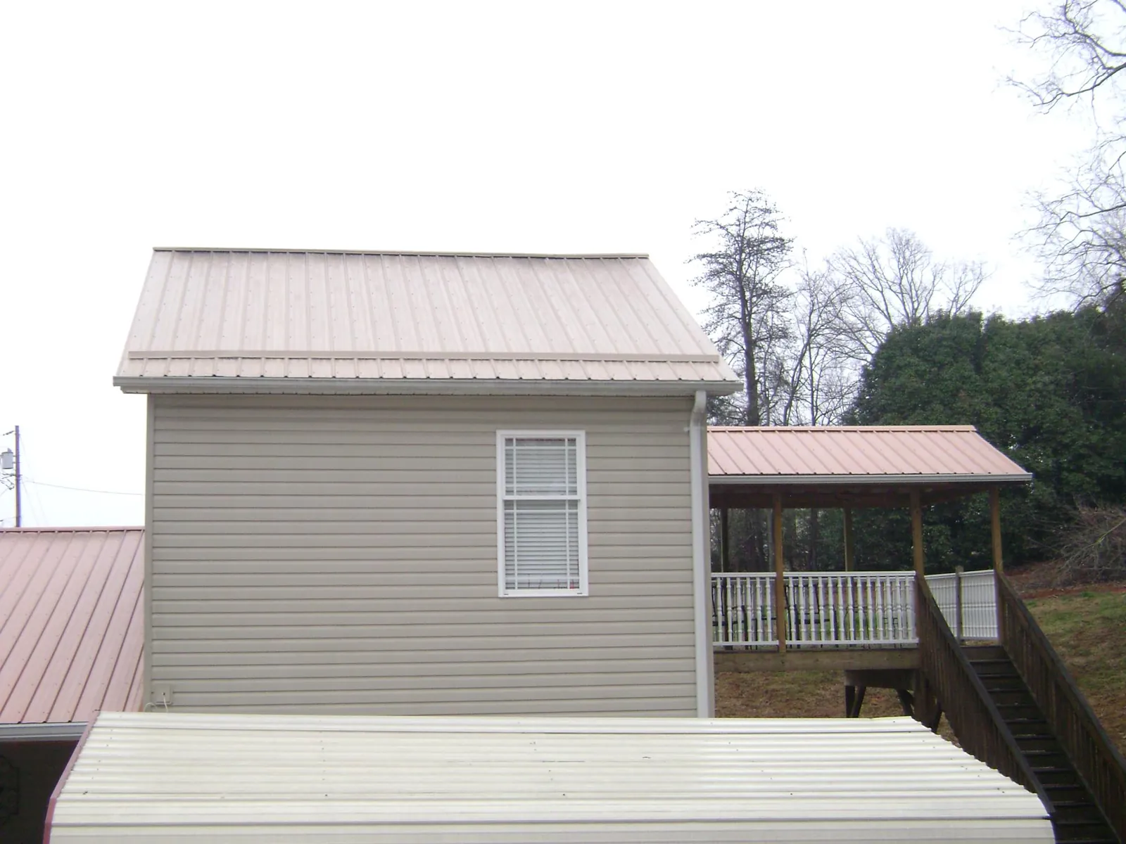 Tan metal roofs on a two story addition and attached porch, from a Roof Replacement job in Jersey